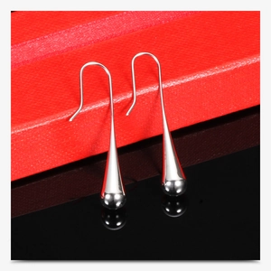 Detailed view of silver teardrop earrings on a red leather gift box with reflections