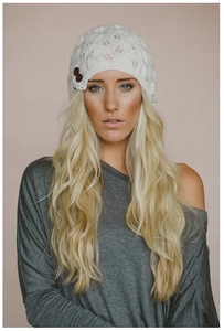 Detailed shot of white knit beanie with leaf pattern and decorative buttons