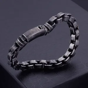 Détail macro du bracelet à maillons en acier rétro sur fond en cuir de crocodile noir