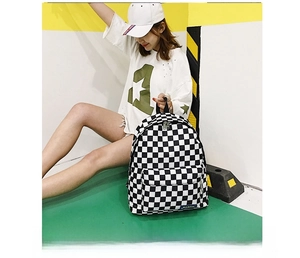 Detalle de la mochila de nailon a cuadros blancos y negros con bolsillos con cremallera