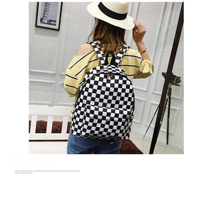 Vista trasera de una modelo con mochila de nailon a cuadros blancos y negros con correas