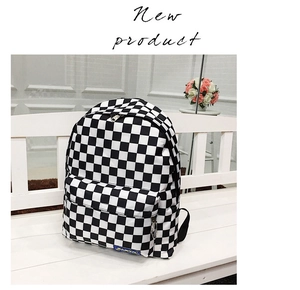 Primer plano de la mochila de nailon a cuadros blancos y negros sobre un banco blanco