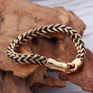 Braided black leather and 18K gold stainless steel bracelet with magnetic clasp on wood