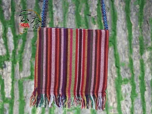 Ethnic shoulder bag featuring colorful vertical stripes and long fringe tassels on wood