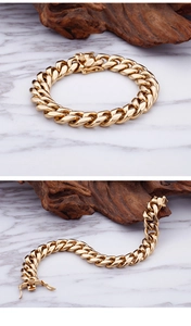 Detail of chunky gold Cuban link bracelet with lobster clasp on marble surface