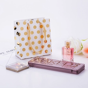 White paper gift bag with gold foil dots shown with perfume and cosmetics set