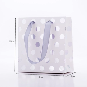Detail of white paper gift bag with silver foil dots and purple ribbons 15x14x7cm