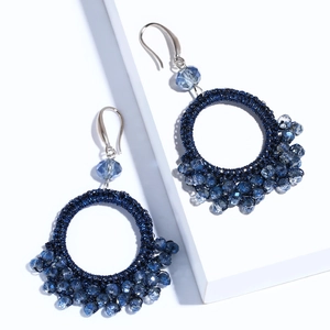 Detailed close-up of woven round earrings with blue crystal beads and silver hooks