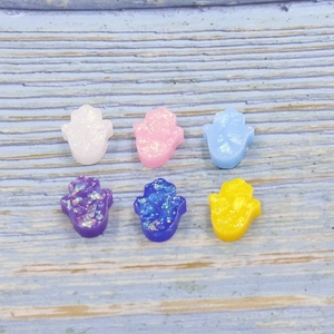 Detailed view of six colorful synthetic opal hamsa hand charms with sparkling glitter inlay