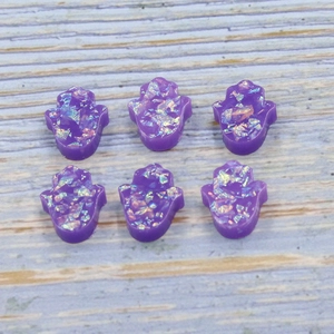 Detailed close-up of six purple resin Hamsa hand opal charms on a blue wood background
