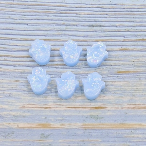 Detail view of blue Hamsa Hand opal beads with iridescent flakes on wood surface