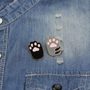 Close-up of cute cat paw enamel brooches pinned on light blue denim shirt pocket