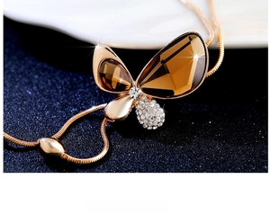 Macro shot of rose gold butterfly pendant with amber crystals and sparkling diamond pavé