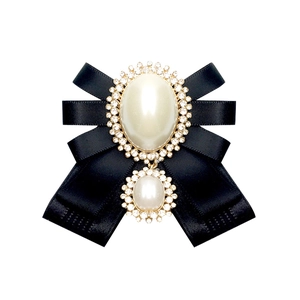 Detail of a vintage black ribbon bow brooch featuring faux pearls and sparkling rhinestones