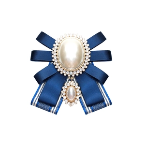Detail of navy blue satin bow brooch with vintage pearl and rhinestone embellishments