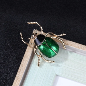 Macro view of beetle brooch featuring green enamel and gold-tone alloy details