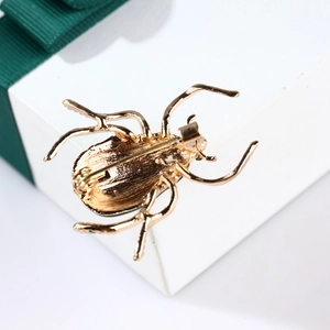 Macro shot of beetle brooch back with secure pin clasp on a white gift box with green ribbon