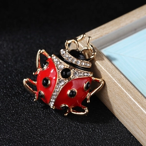 Close-up of red enamel ladybug brooch with sparkling rhinestones and gold-plated finish