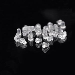 Macro shot of clear silicone earring back stoppers on a reflective black surface
