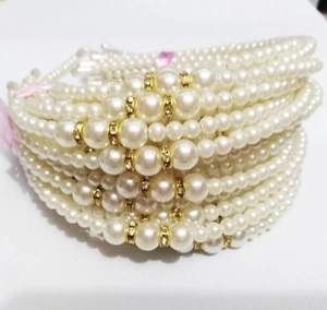Close-up of stacked white pearl bracelets with golden rhinestone spacers for kids