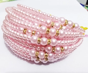 Detail view of pink pearl hairband strands with gold gemstone-encrusted spacer beads