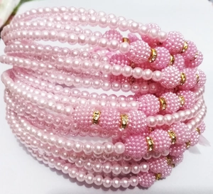 Close-up of pink layered faux pearl headband with decorative gold ring accents