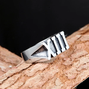 Polished silver stainless steel men's ring with Roman numeral XIII on rough tree bark