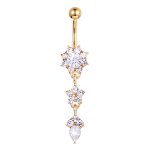 Detail of golden flower belly ring with star charms and sparkling teardrop pendant
