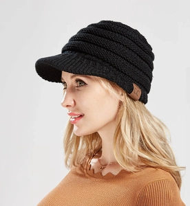 Detail view of a black chunky knit ponytail beanie with a leather C.C logo patch and visor