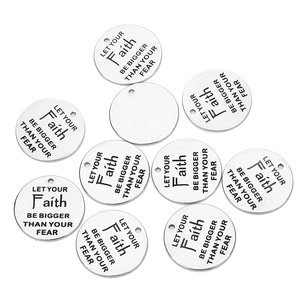 Macro detail of round silver stainless steel charms with faith over fear engraving