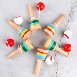 Set of seven wooden kendama cup and ball toys with colorful stripes on concrete background