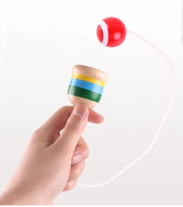 Detailed view of hand holding wooden cup and ball toy with red ball and striped cup