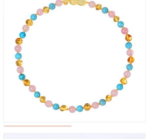 Détail du collier pour bébé montrant des perles d'ambre et de quartz rose poli