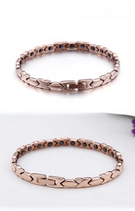 Macro shot of rose gold magnetic therapy bracelet with X-link pattern and snap buckle