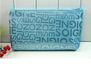 Blue cosmetics bag featuring repeated SOIGNE letter patterns with a secure zipper closure