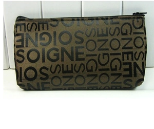 Detailed close-up of brown jacquard cosmetic bag with black zipper and letter patterns