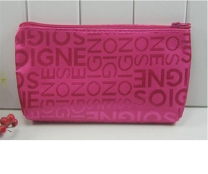 Front view of a pink jacquard fabric makeup bag with repeating DIGNE letter patterns