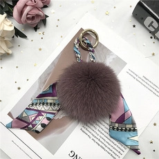 Detail of purple mink fur pom pom keychain with silk scarf and gold ring hardware