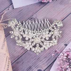 Detailed view of bridal hair comb with pearls and rhinestones on a rustic wood surface