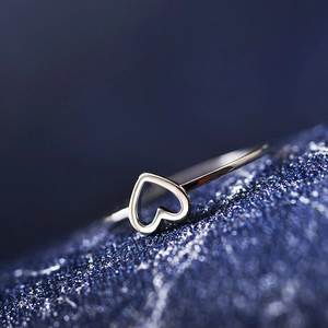Macro close-up of minimalist hollow heart silver ring on a starry blue background