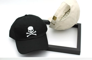 Detail of cotton baseball caps showing embroidered skull logo and adjustable metal buckle