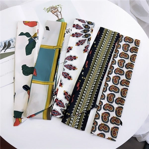 Collection of long silk scarves with floral and geometric prints on a white table