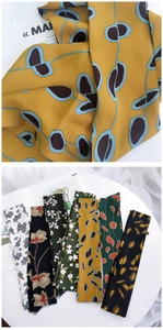 Detailed view of silk-like neck scarves with diverse floral and geometric patterns
