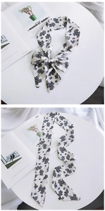 Detail of white silk scarf with blue floral pattern tied in a bow and flat layout