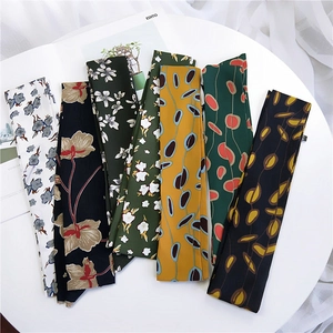Floral skinny silk scarves for women with various elegant leaf patterns on a table