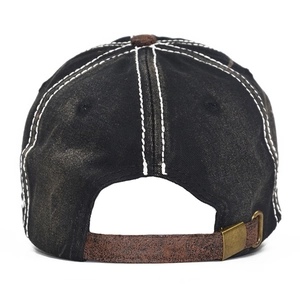 Close-up of adjustable brown leather strap and bronze buckle on washed denim baseball cap
