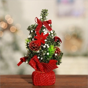 Mini tabletop Christmas tree with red bows and berries on a festive red base