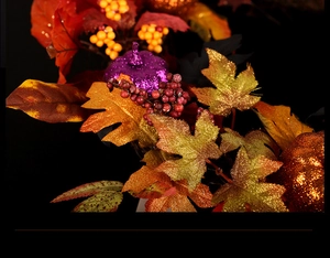 Close-up of glitter pumpkins and autumn maple leaves on a decorative festive wreath