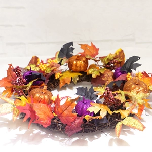 Fall wreath with maple leaves and pumpkins on a natural rattan base for home decor