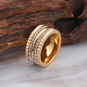 Elegant multi-layer gold plated ring with crystal zircon stones on a wooden background